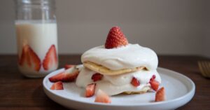 Close-up of a strawberry shortcake with whipped cream and fresh strawberries.